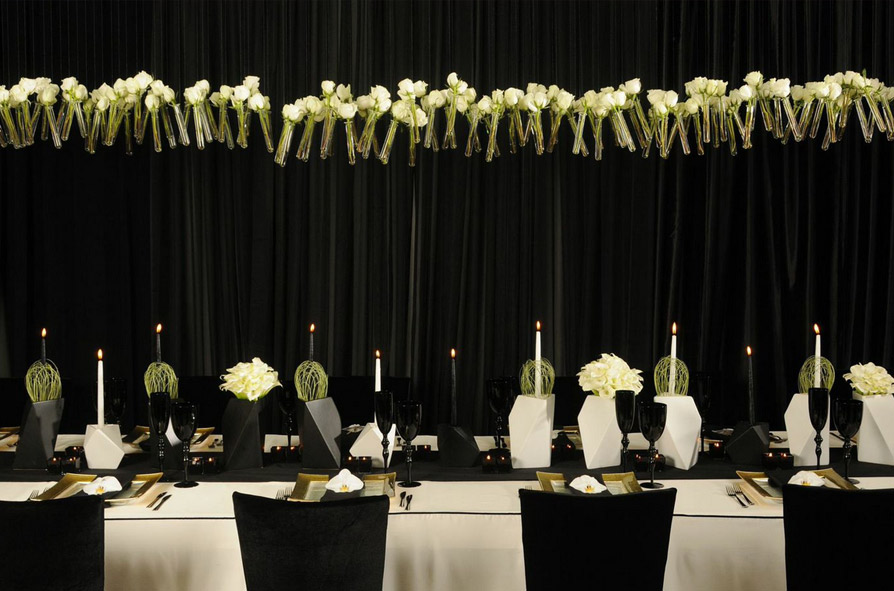 Monochromatic themed table featuring floating glass tubes filled with roses.
